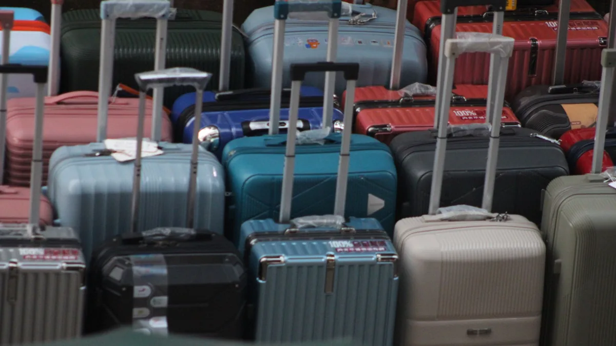 Rows of hard-shell suitcases in blue, grey, pink and black standing together with their handles extended