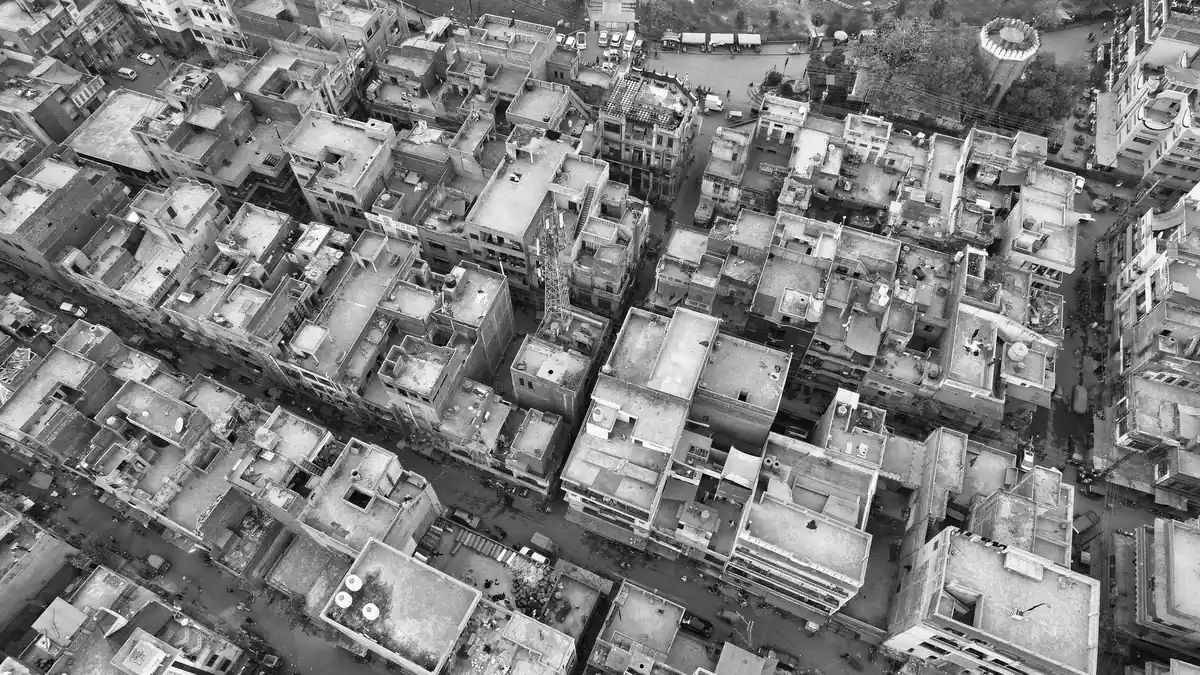Black and white aerial view of densely packed homes, rooftops and narrow streets in a Lahore neighbourhood