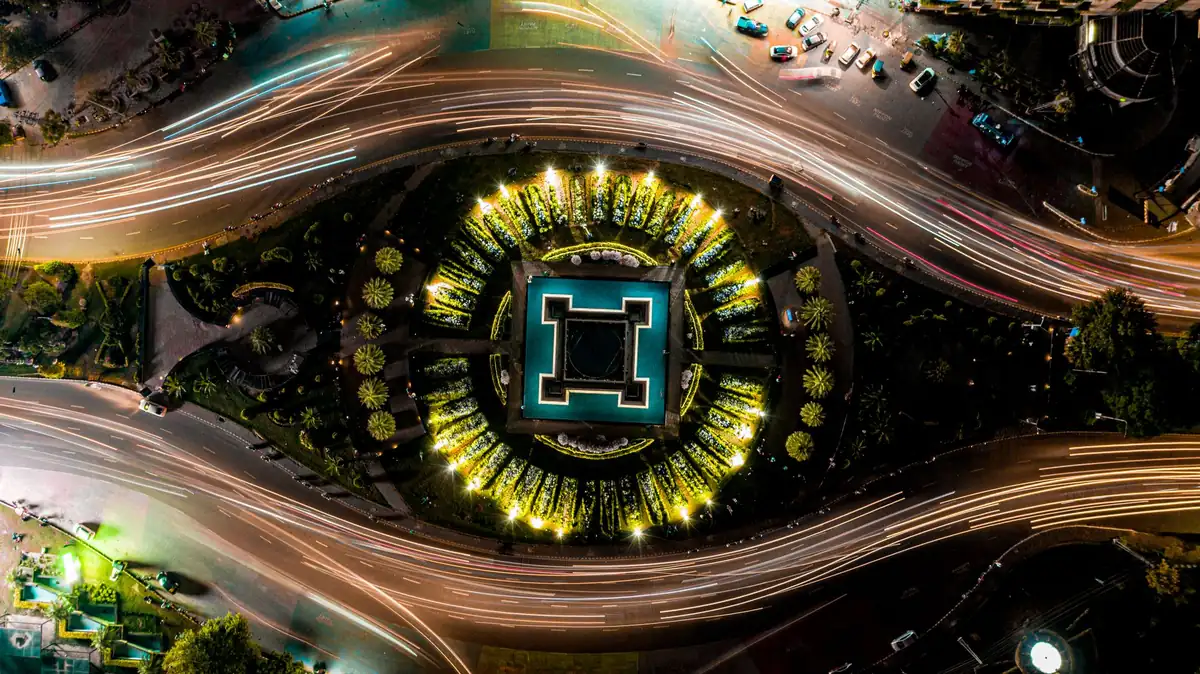 Aerial night view of an illuminated roundabout in Lahore with light trails from traffic circling it