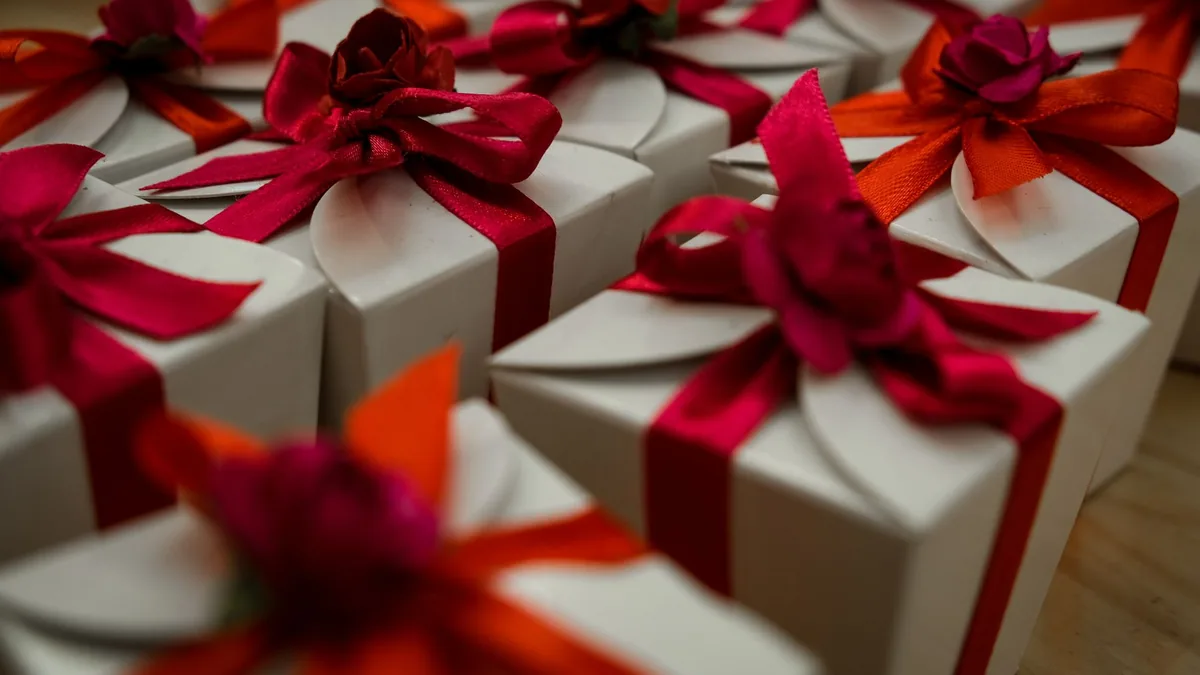 Rows of white gift boxes tied with red and orange satin ribbons and flower bows, ready to be packed and moved