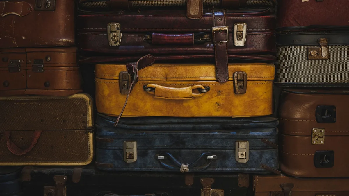 A tall wall of stacked suitcases in brown, yellow and navy, showing how much space a group's luggage takes up