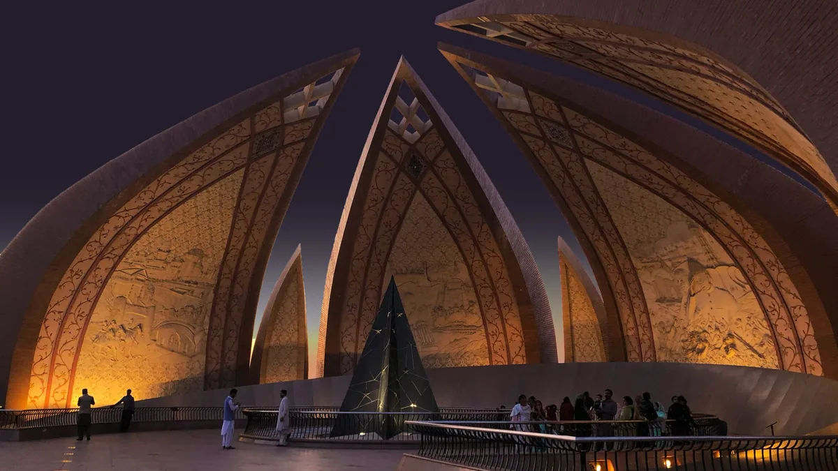Pakistan Monument in Islamabad lit at dusk, its curved granite petals glowing above visitors on the plaza