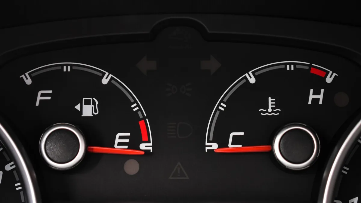 Close-up of a car instrument cluster with the fuel gauge needle resting on E beside the temperature gauge
