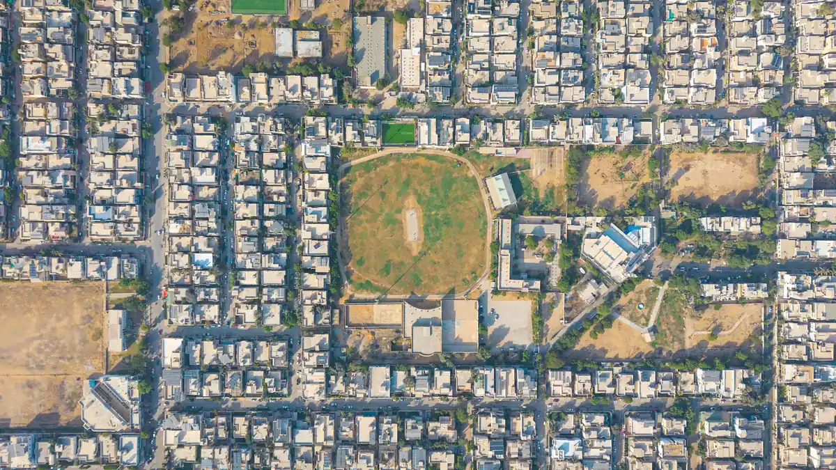 Aerial view of a dense residential neighbourhood with tightly packed houses, narrow streets and an oval cricket ground