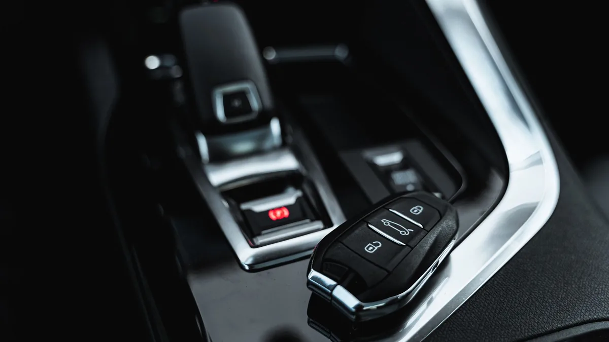 Close-up of a black car key fob resting on a car's centre console beside the gear selector