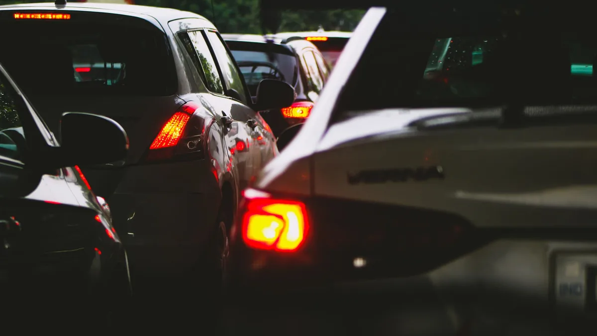 Close-up of cars queued bumper to bumper in slow traffic at dusk, red brake lights glowing