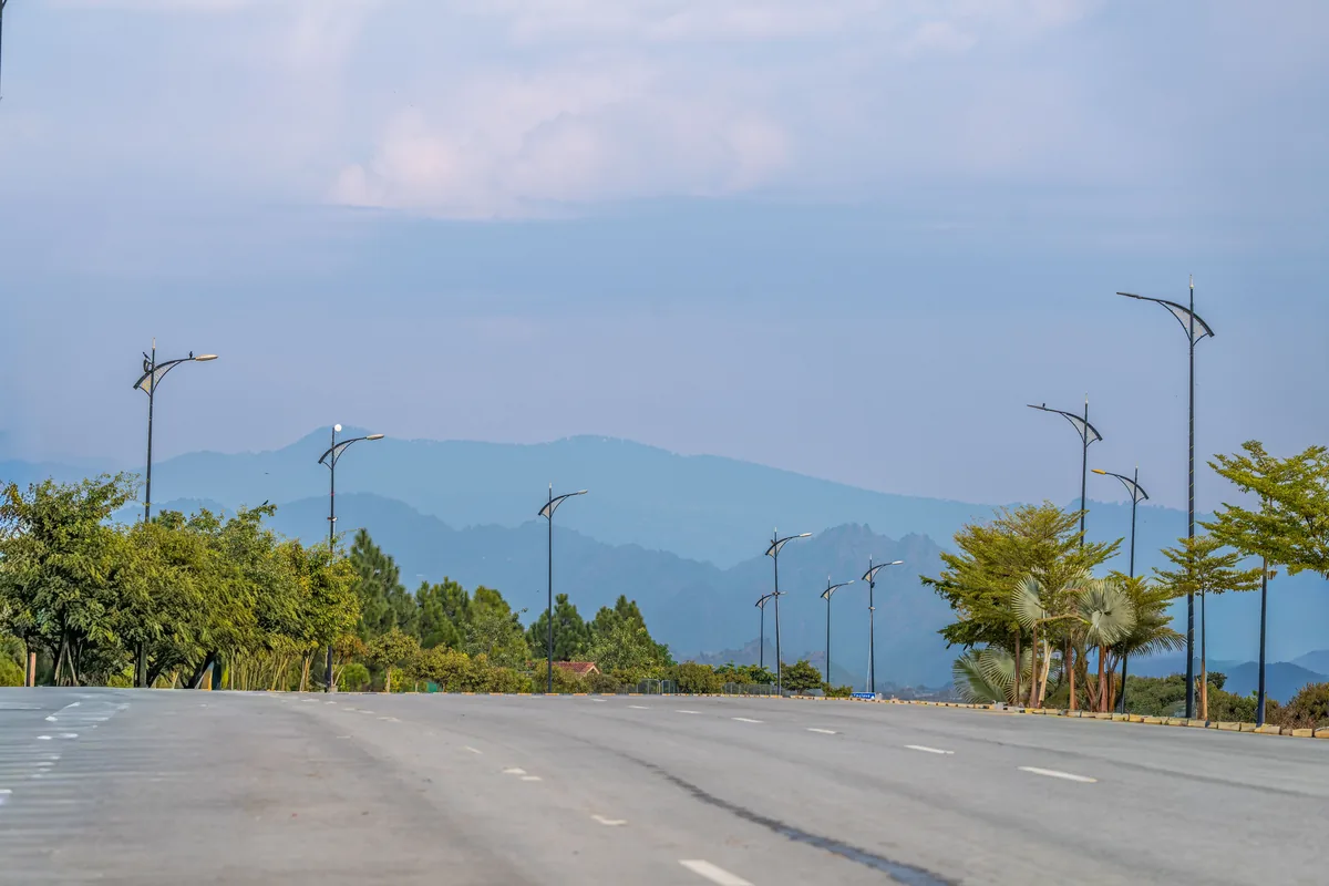A tree-lined Islamabad boulevard leading towards the Margalla Hills