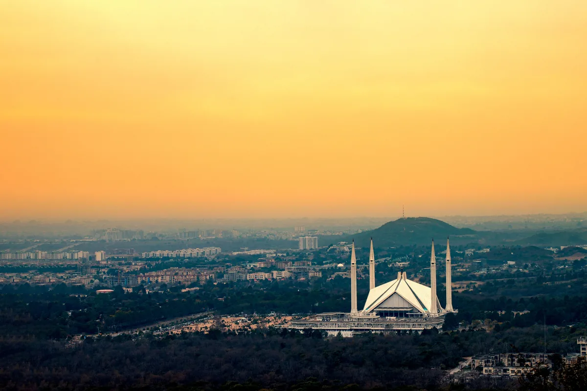 Faisal Mosque and the Islamabad skyline beneath a golden sky