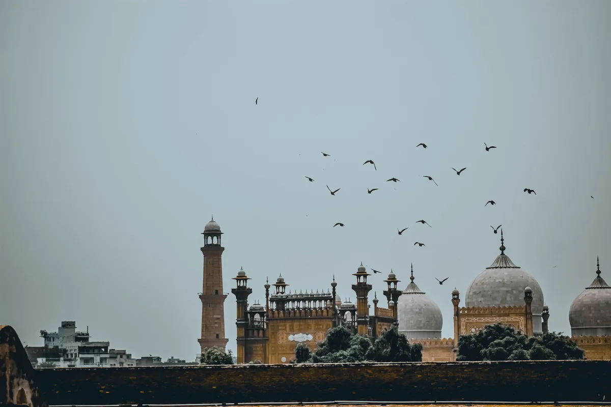 Domes and minarets of Badshahi Mosque with birds overhead