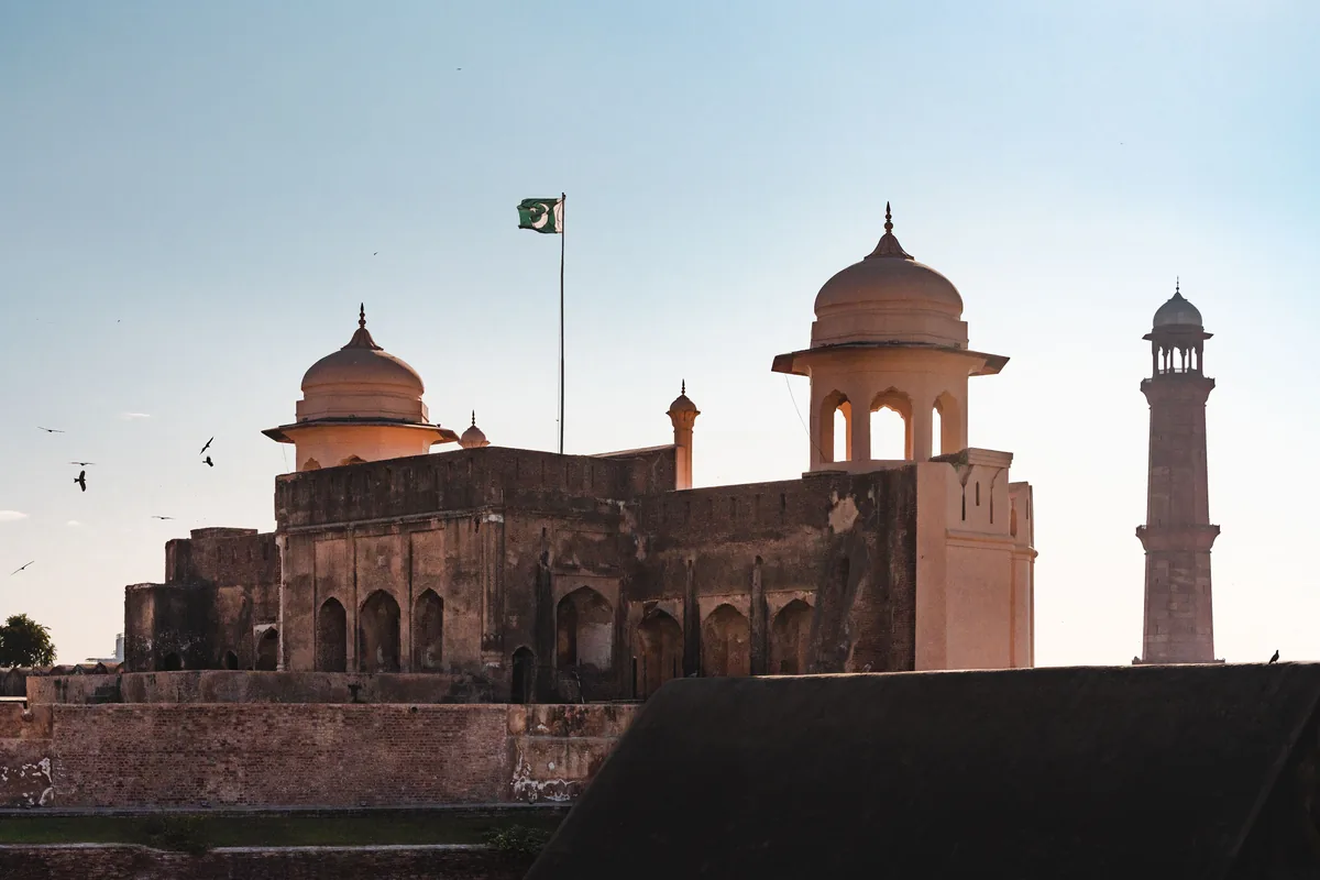 The entrance to Lahore Fort beneath the Pakistan flag at sunset