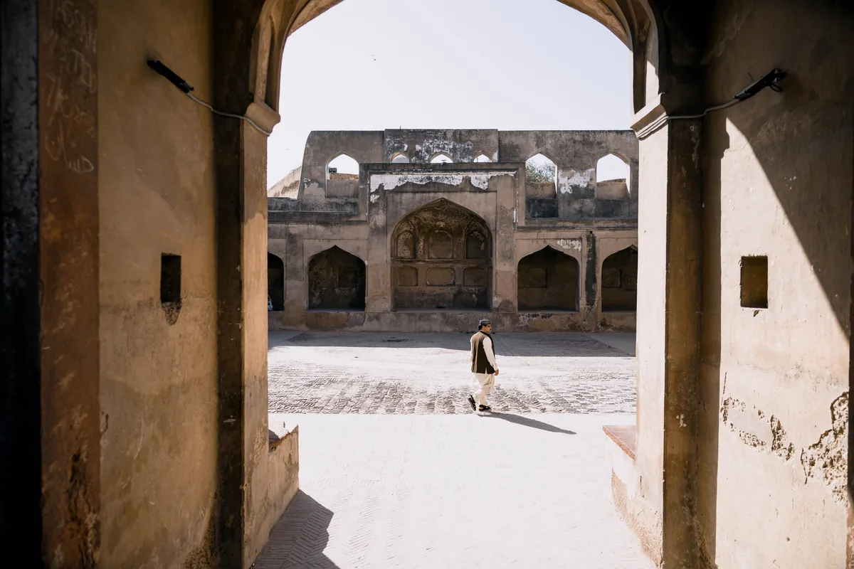 A Lahore courtyard viewed through a shaded stone arch