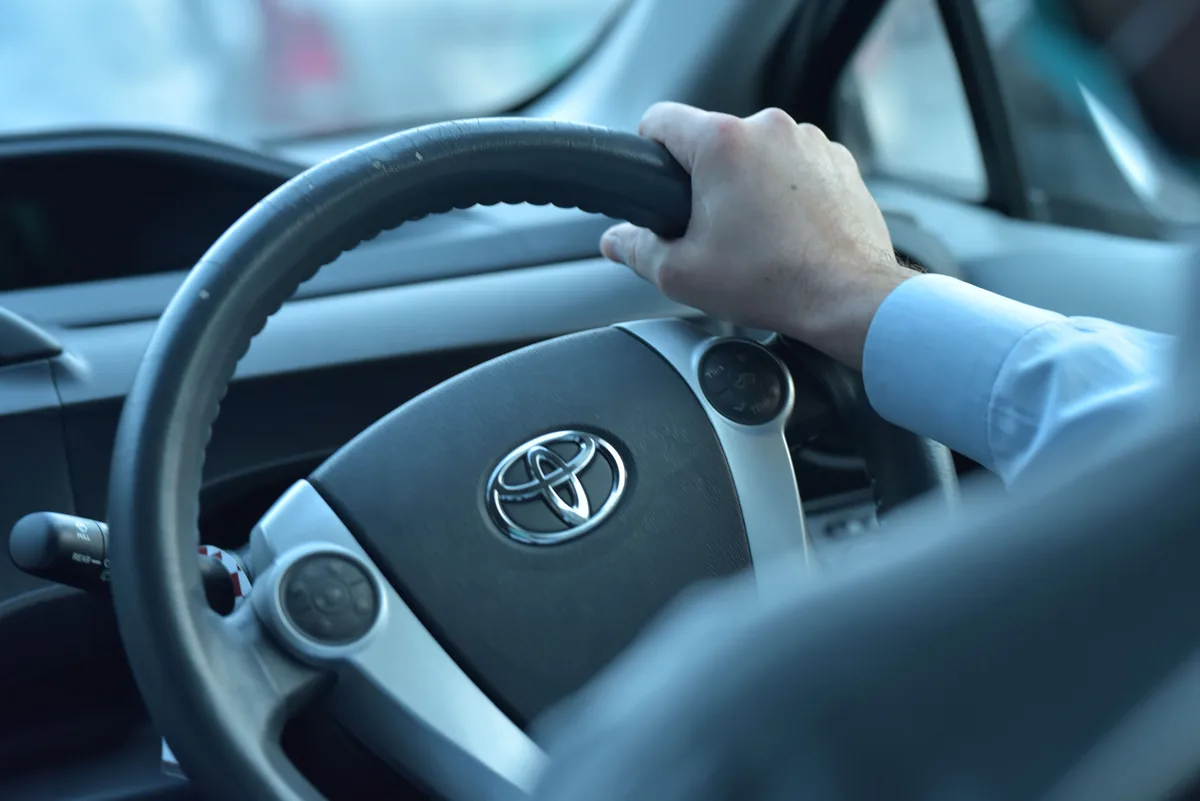 Preparing for a drive A hand resting on a car steering wheel, photographed in Faisalabad