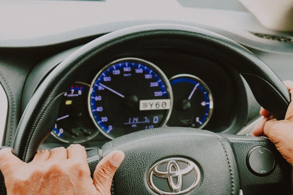Hands on a steering wheel with dashboard instruments in view