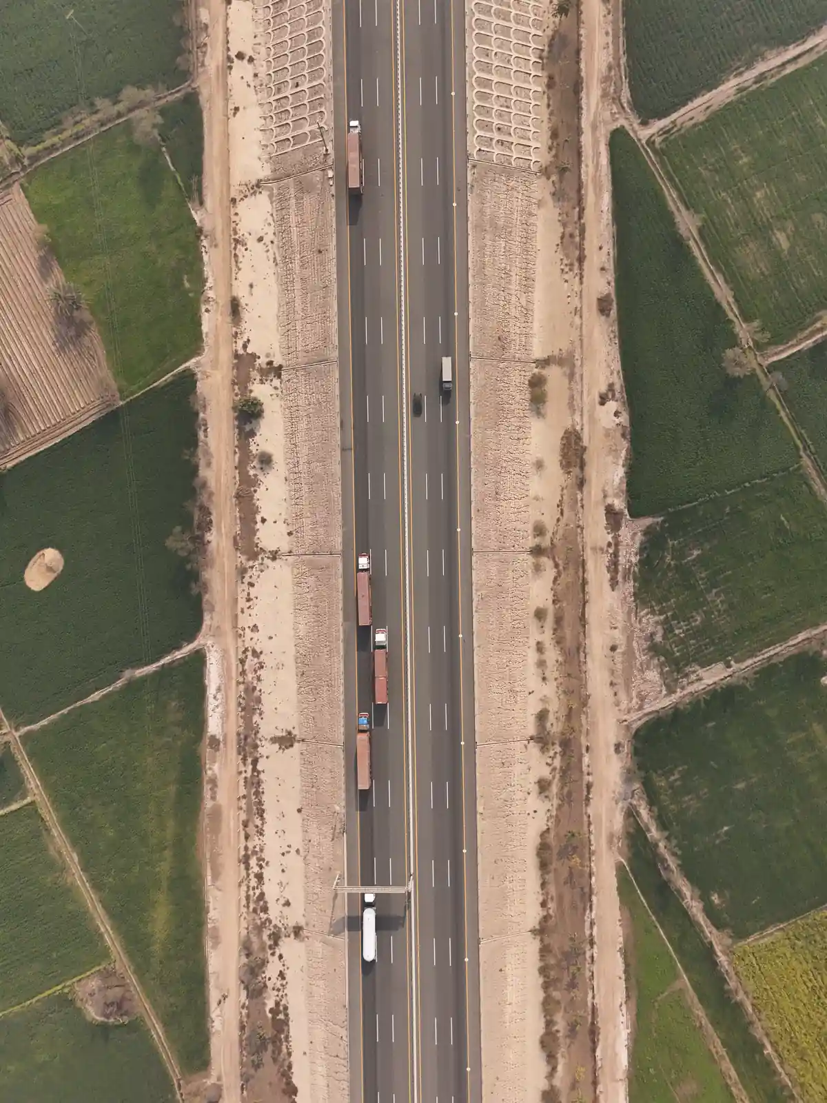 Drone view of vehicles on a motorway between green fields in Punjab