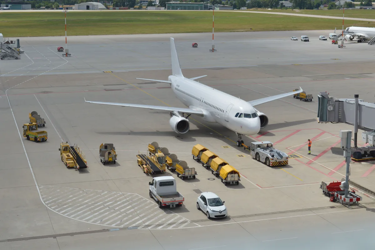 Passenger aircraft parked beside airport service vehicles