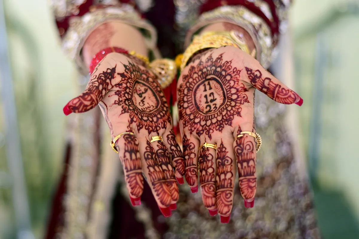 Two henna decorated palms held up during a wedding