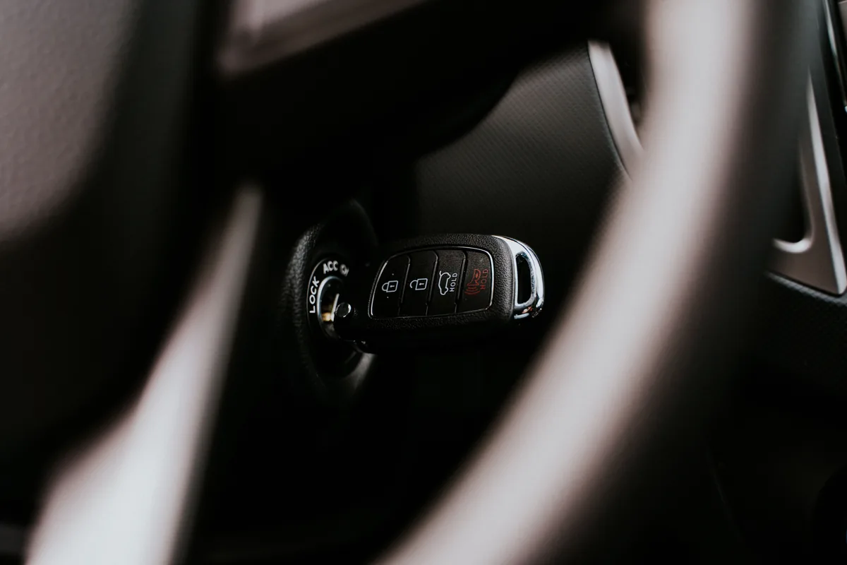 Close view of a car key in an ignition behind a steering wheel