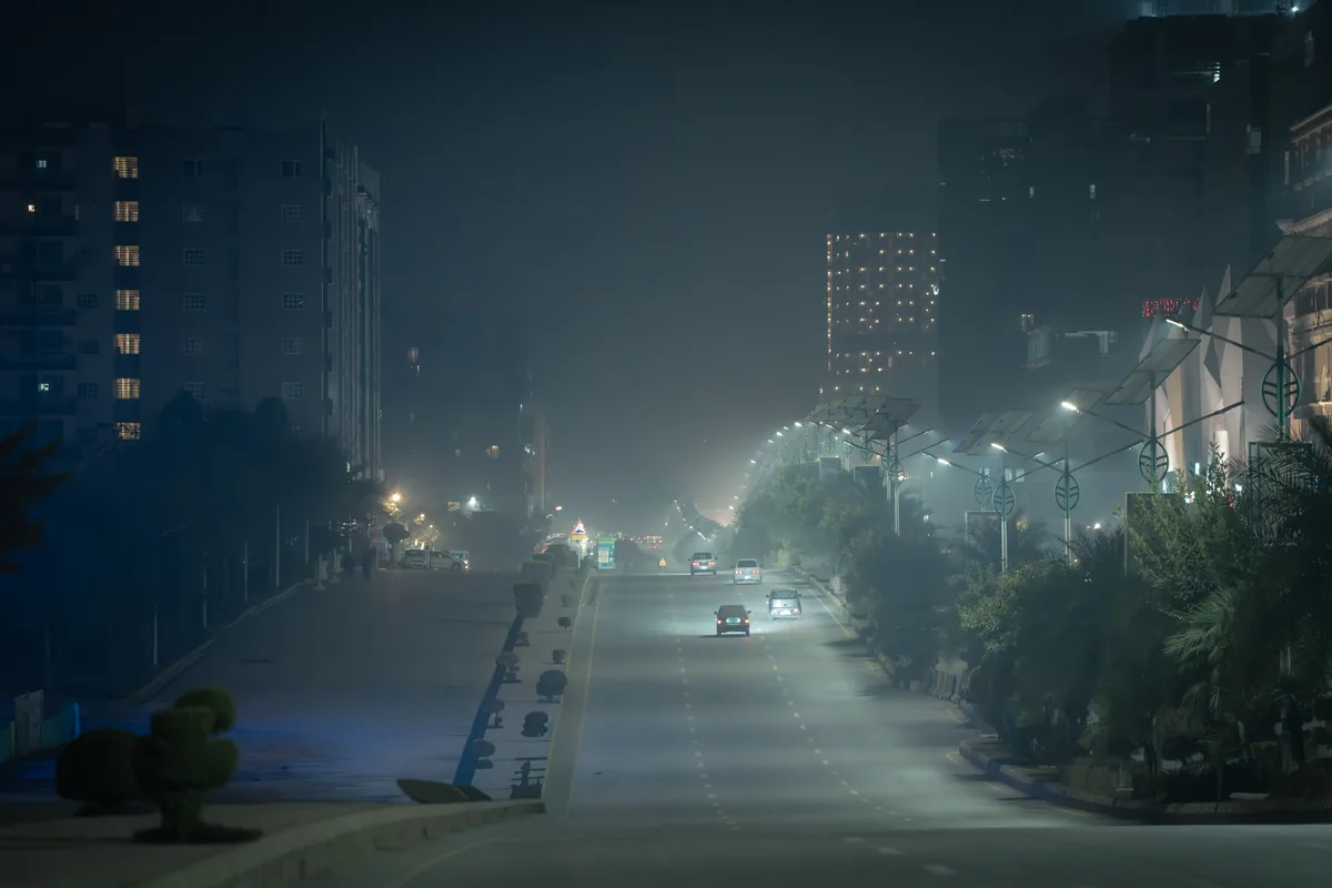 Hazy Karachi street lit by lamps after dark