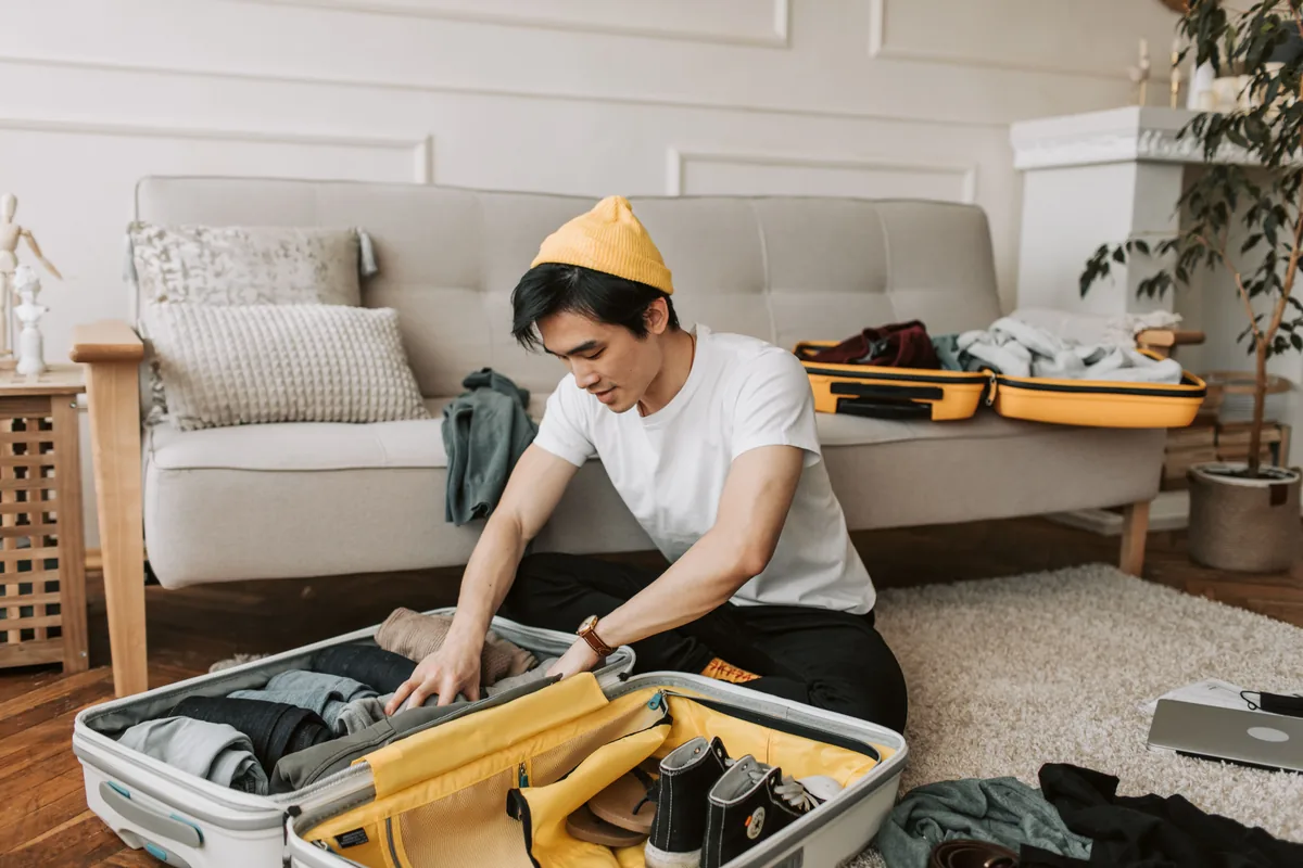 Person placing clothes into an open suitcase at home