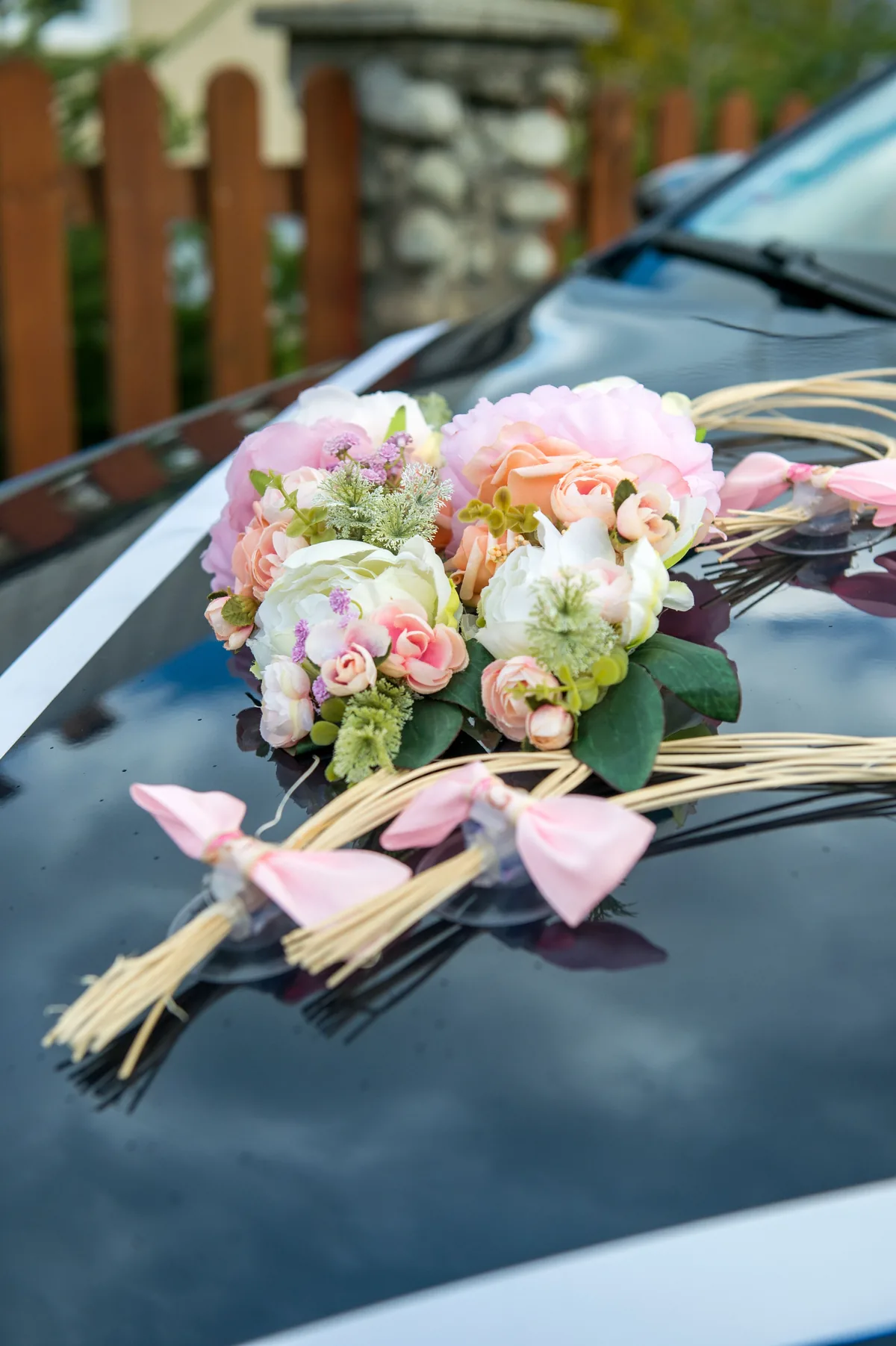 Pastel flower arrangement attached to a dark car bonnet