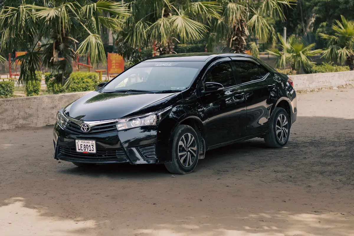 A Toyota Corolla in Punjab A black Toyota Corolla parked among greenery, Punjab registration plate visible